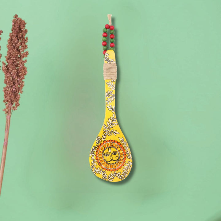 Click to see full view    Indha Hand-Painted Wooden Spoon Décor – Madhubani Sun Art | Yellow Wall Accent with Jute & Beads | Travel-Friendly Indian Souvenir | Handmade Gift