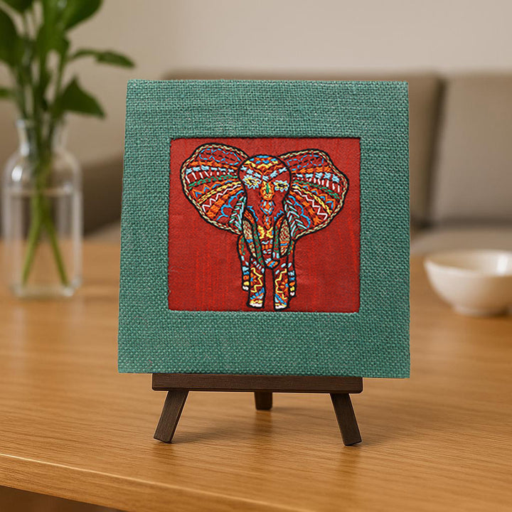 Indha Hand-Embroidered African Elephant – Silk Textile Art with Mini Wooden Easel A vibrant elephant motif stitched on rich silk—tabletop ready, gift-ready